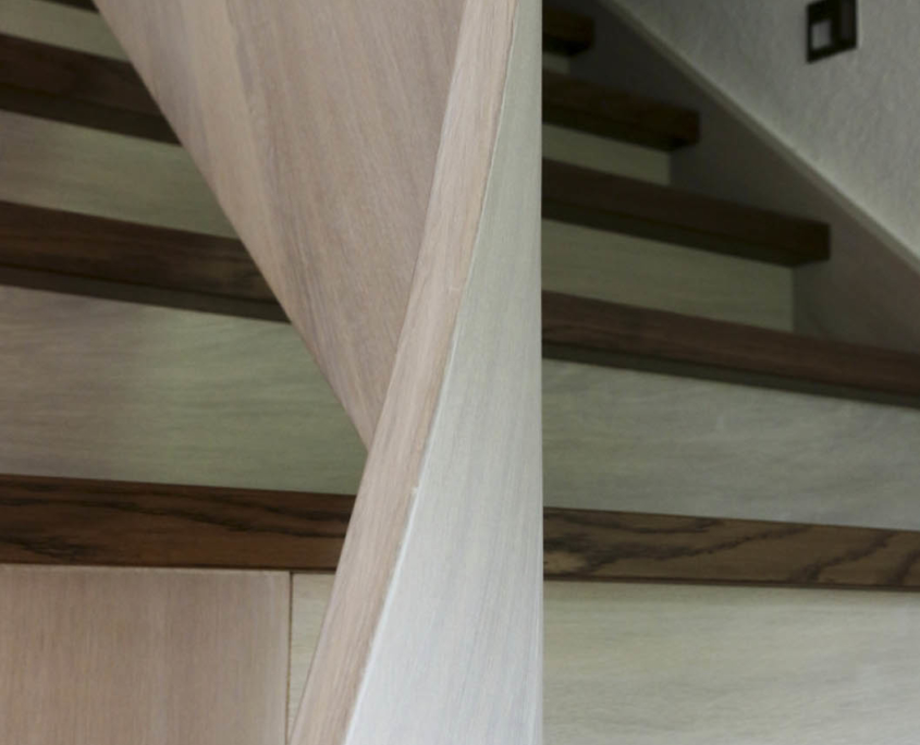Aufgesattelte Treppe in Massivholz Eiche viertelgewendelt, mit gebogenem Geländer aus Brettschichtholz, Oberfläche mit hell und dunkel pigmentiertem Lack